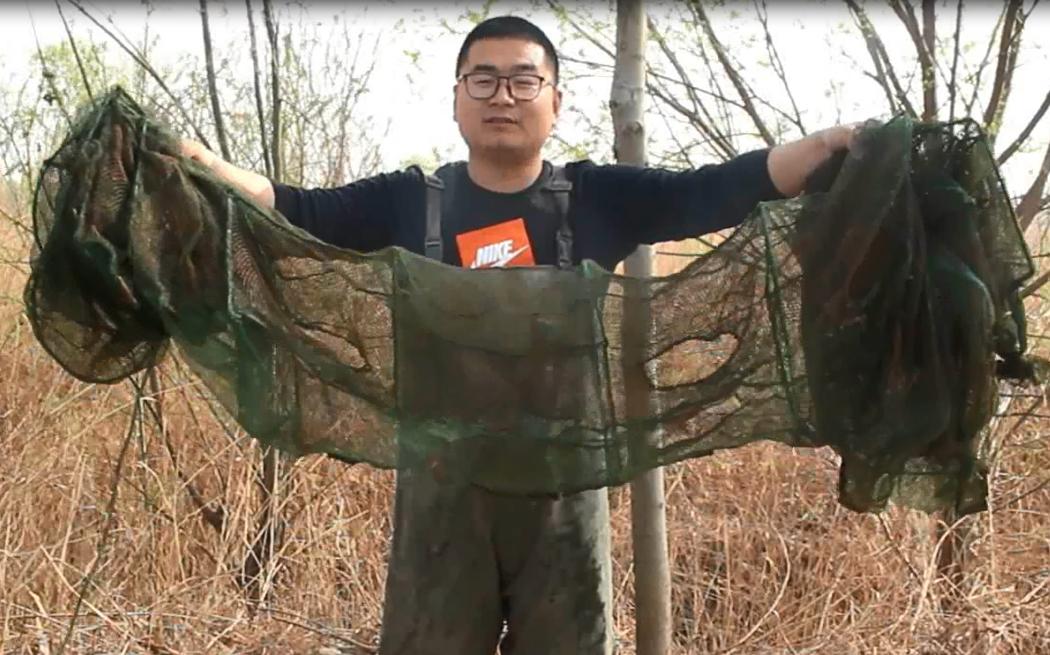 农村小伙在河里抓到一只小鱼,农村小伙河中发现废弃地笼